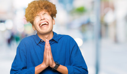 Naklejka premium Young handsome elegant man with afro hair begging and praying with hands together with hope expression on face very emotional and worried. Asking for forgiveness. Religion concept.