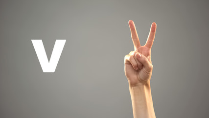 Letter V in sign language, hand on background, communication for deaf, lesson