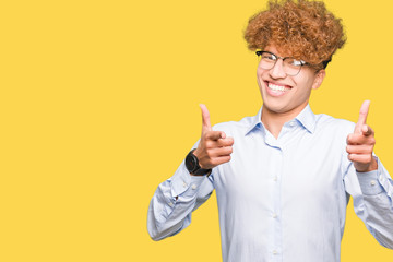 Young handsome business man with afro wearing glasses pointing fingers to camera with happy and funny face. Good energy and vibes.