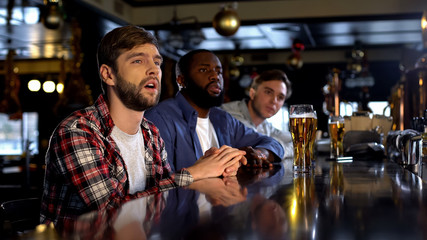 Unhappy male friends watching championship in bar, team losing game, failure