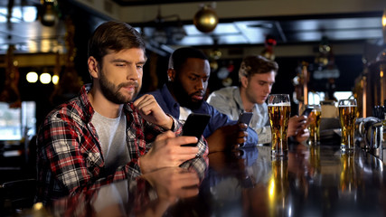 Anxious male fans betting on phone, watching game in pub, gambling application