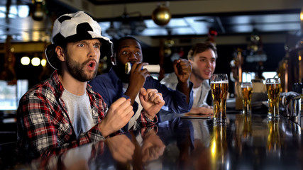 Male soccer fans watching tournament in bar expecting scoring goal, championship