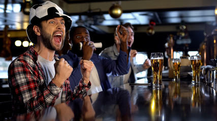 Extremely happy soccer fans watching game in pub, celebrating scoring goal