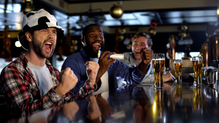 Cheerful football fans supporting favorite team in pub happy about victory, rest