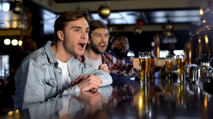 Male friend watching tournament in pub, cheering for victory of national team