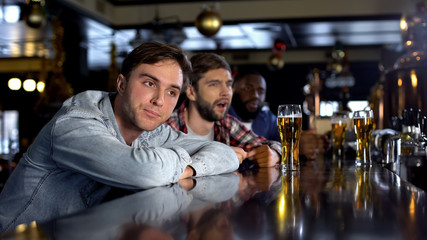 Disappointed male friends watching game in pub, disappointed with losing match