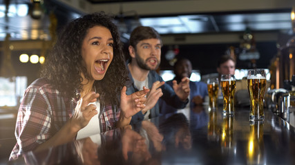 Beautiful biracial lady celebrating favorite team winning game, relaxing in pub - Powered by Adobe
