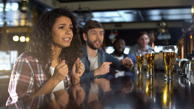 Pretty biracial lady watching game in pub, happy time with friends, togetherness