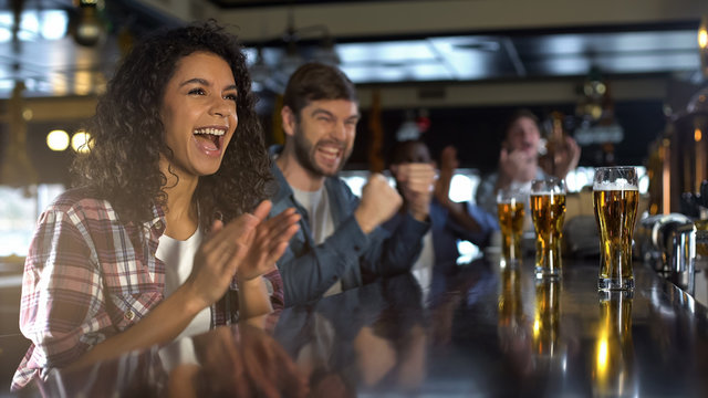 Attractive lady and male friends celebrating team winning game, time in pub