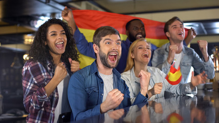 Extremely happy Spanish supporters waving national flag, celebrating victory