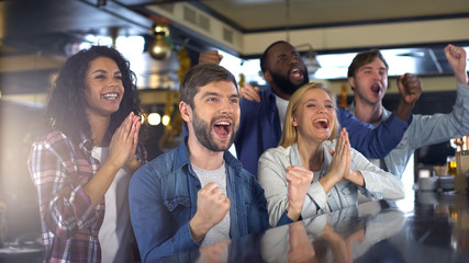 Group of sport fans watching game in bar, rejoicing victory of favorite team