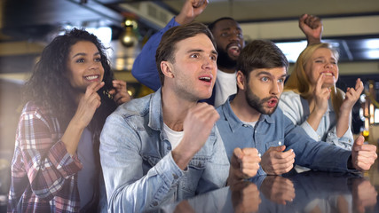 Friends crossing fingers watching sport championship in bar, supporting team