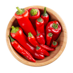Red pepper in wooden bowl isolated on white background. Top view,  close-up. Ramiro and chili pepper.