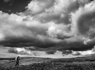 Fototapeta na wymiar Lonely hiker walking under epic clouds