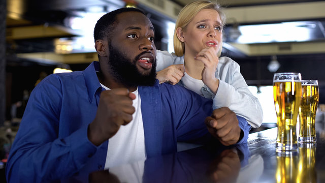 Nervous biracial couple supporting favorite sport team, watching match online