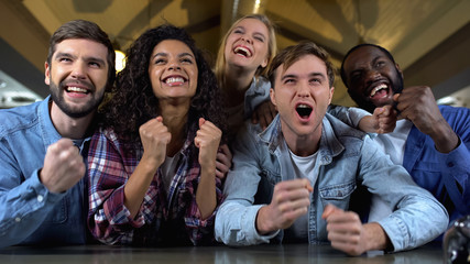 Positive young people rooting for team goal, watching match together, audience