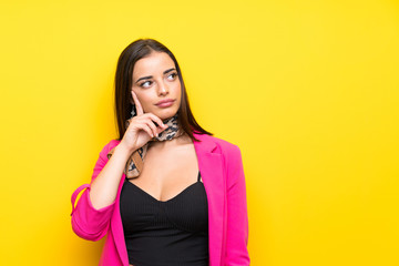 Young woman over isolated yellow background thinking an idea