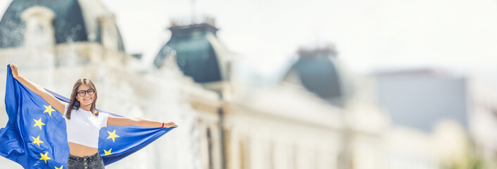 Cute happy young girl with the flag of the European Union in front of a historic building somewhere...