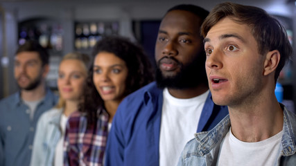Concentrated supporters attentively watching tv, waiting for contest results