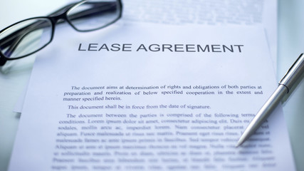 Lease agreement lying on table, pen and eyeglasses on official business document