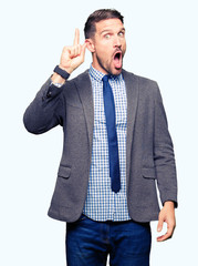 Handsome business man wearing suit and tie pointing finger up with successful idea. Exited and happy. Number one.