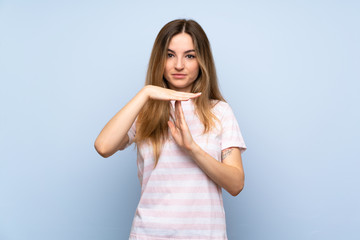 Young woman over isolated blue background making time out gesture