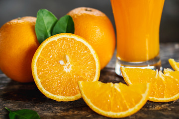 orange sliced and orange juice glasses with green leaf on wooden table 
