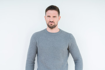 Young handsome man wearing casual sweater over isolated background skeptic and nervous, frowning...