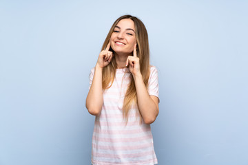 Fototapeta premium Young woman over isolated blue background smiling with a happy and pleasant expression