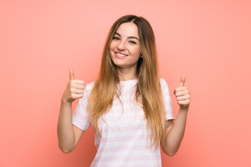 Young woman over isolated pink wall giving a thumbs up gesture