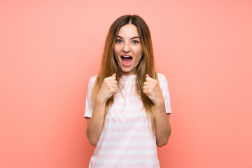 Fototapeta premium Young woman over isolated pink wall celebrating a victory