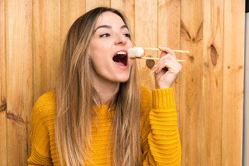 Young woman with sushi over wood background © luismolinero
