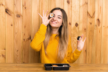 Young woman with sushi over wood background © luismolinero
