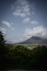 Mountain landscape looking on small villages, clouds cast shadows, warm summer day