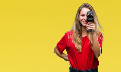 Young beautiful blonde woman filming using vintage camera over isolated background with a happy...