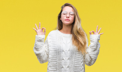 Young beautiful blonde woman wearing winter sweater and sunglasses over isolated background relax and smiling with eyes closed doing meditation gesture with fingers. Yoga concept.