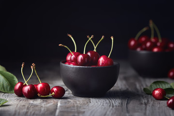 Ripe red cherries in a bowl and next to it