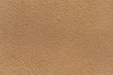Old light sand wall covered with shabby uneven plaster. Texture of vintage golden stone surface.