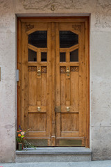 an art deco wooden door of a building with a bouquet of flowers, in Madrid. Spain