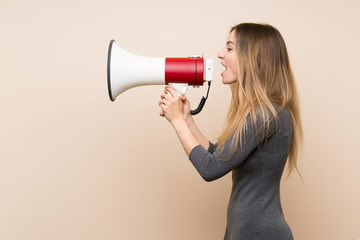 Young woman over isolated background shouting through a megaphone