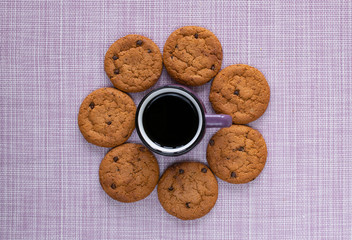 A small purple cup of coffee and mouth-watering avatina cookies with chocolate crumb on a pink napkin