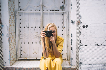 Caucasian woman making photo near white ancient door while spending time for exploring berber...
