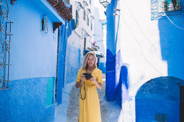 Portrait of woman with retro camera enjoying free day in Chaouen historic center, positive female...