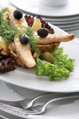Festive snack white fish tartlet on a white plate decorated with olives, lemon and parsley.
