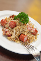German, Polish, Austrian cuisine dish, Bigos - cabbage stewed with meat and sausages on a white plate