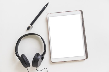 Fototapeta na wymiar Digital with blank screen; stylus pen and headphone on white backdrop