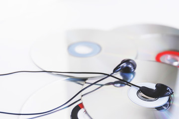 Black earphone on compact disc against white background