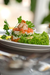 Olivier salad with shrimps, eggs and vegetables on a white plate. Depth of field