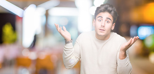 Fototapeta premium Young handsome man over isolated background clueless and confused expression with arms and hands raised. Doubt concept.