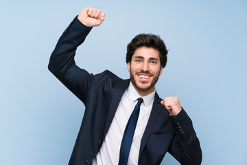 Businessman over isolated blue wall celebrating a victory